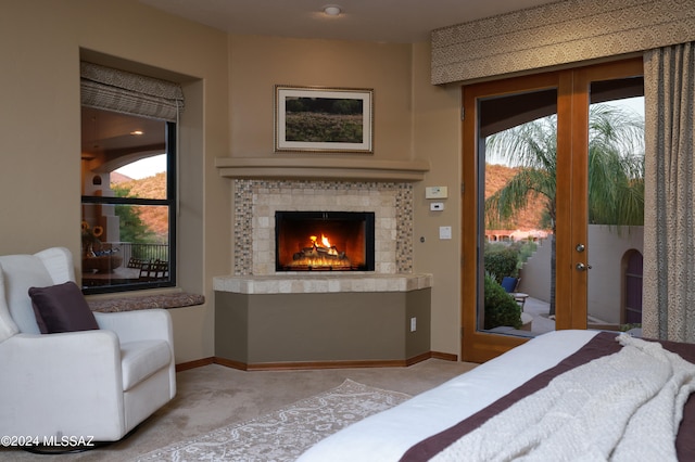 bedroom featuring a tiled fireplace, access to exterior, and light colored carpet