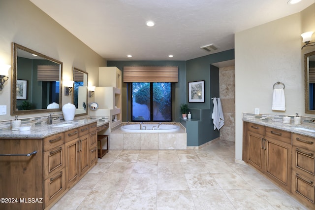 bathroom with vanity, a relaxing tiled tub, and tile patterned flooring