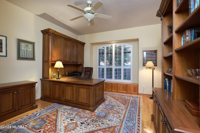 office space featuring light hardwood / wood-style floors, built in desk, and ceiling fan