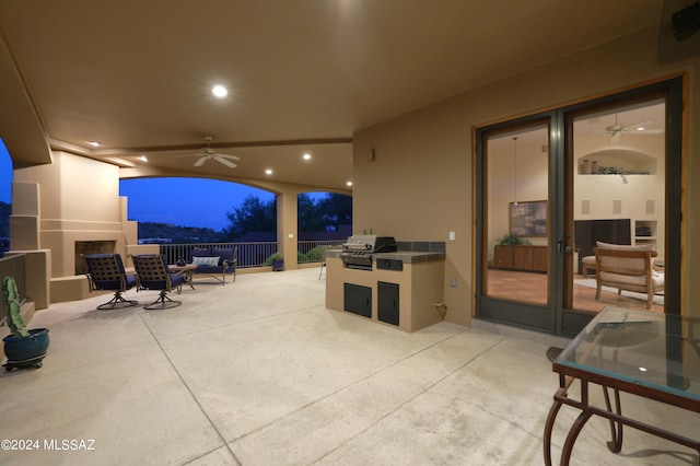 patio terrace at dusk featuring area for grilling and ceiling fan