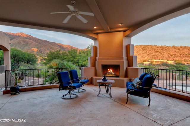 view of patio / terrace featuring a balcony, a mountain view, a fireplace, and ceiling fan