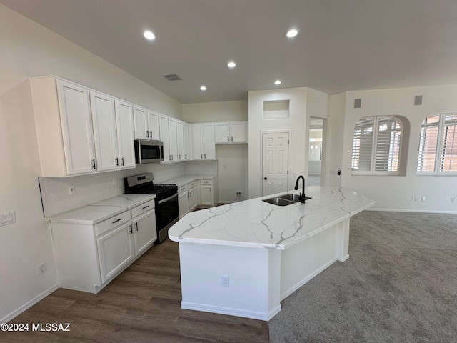 kitchen featuring stainless steel appliances, a center island with sink, sink, dark carpet, and light stone countertops