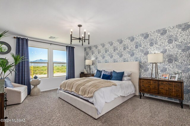 carpeted bedroom featuring connected bathroom and a chandelier