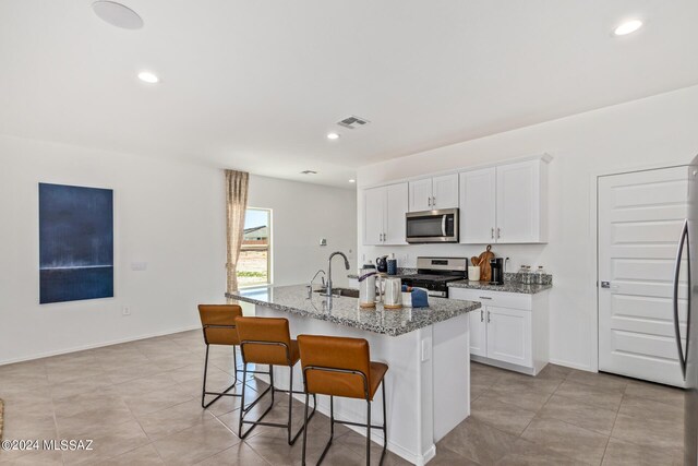 kitchen with sink, white cabinetry, light stone counters, a center island with sink, and dishwasher