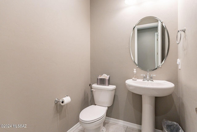 half bathroom featuring tile patterned flooring, baseboards, a sink, and toilet