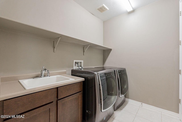 clothes washing area with independent washer and dryer, a sink, light tile patterned flooring, visible vents, and cabinet space