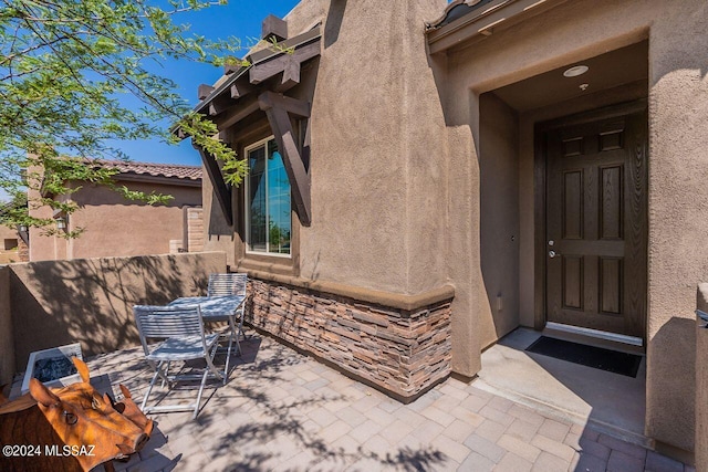 property entrance featuring a patio, outdoor dining space, fence, and stucco siding