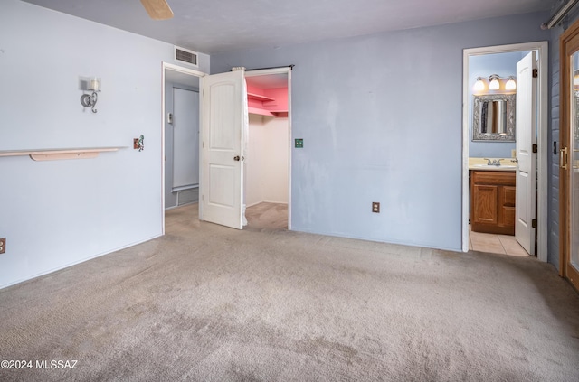 unfurnished bedroom with light carpet, ensuite bath, ceiling fan, and sink