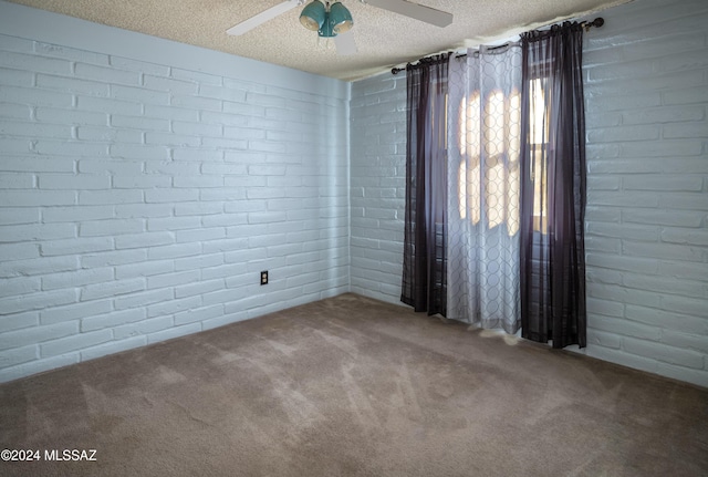 spare room featuring carpet, a textured ceiling, ceiling fan, and brick wall