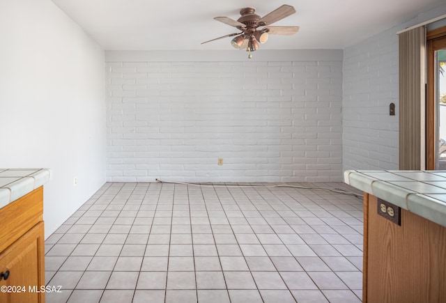 interior space with ceiling fan and brick wall