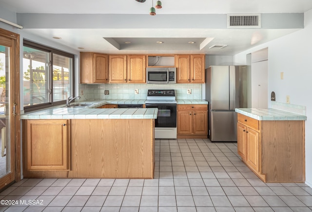 kitchen with tile countertops, stainless steel appliances, and a tray ceiling