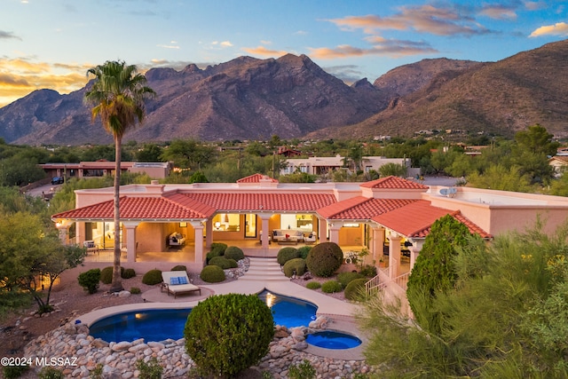 exterior space featuring an in ground hot tub, a mountain view, and a patio