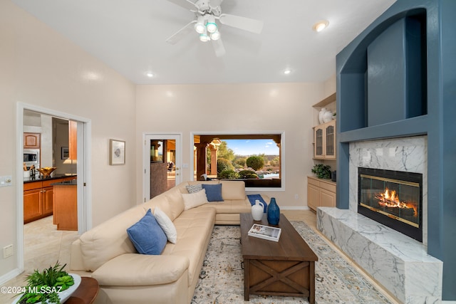 living room featuring a high end fireplace and ceiling fan