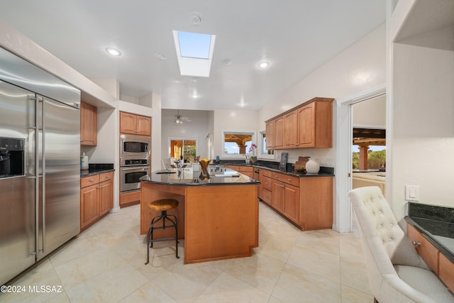 kitchen featuring a center island, a breakfast bar area, a skylight, built in appliances, and light tile patterned floors