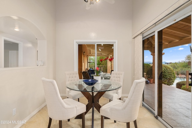 tiled dining room with wood ceiling, high vaulted ceiling, and a healthy amount of sunlight