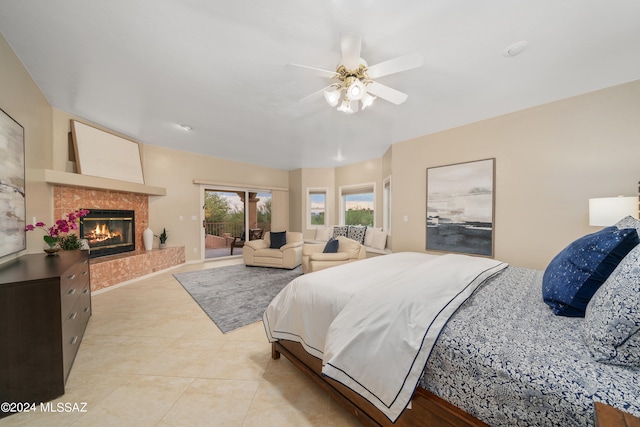 bedroom featuring a fireplace, access to outside, light tile patterned floors, and ceiling fan