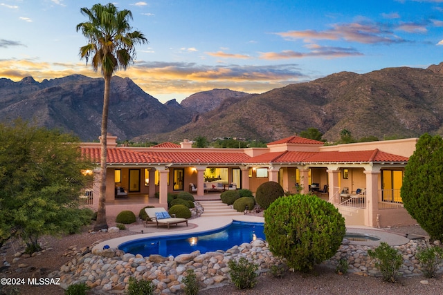 pool at dusk featuring a mountain view and a patio