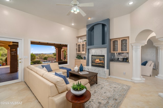 living room with ceiling fan, light tile patterned floors, high vaulted ceiling, decorative columns, and a fireplace