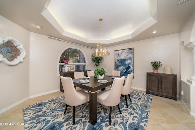 dining space featuring ornate columns, a tray ceiling, and light tile patterned floors