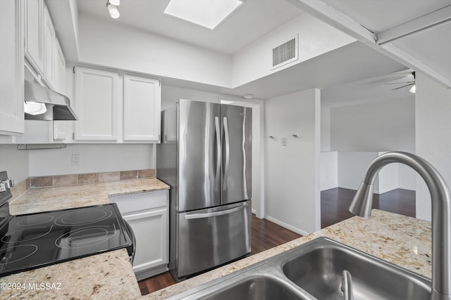 kitchen featuring white cabinetry, a skylight, stainless steel fridge, range with electric cooktop, and light stone countertops