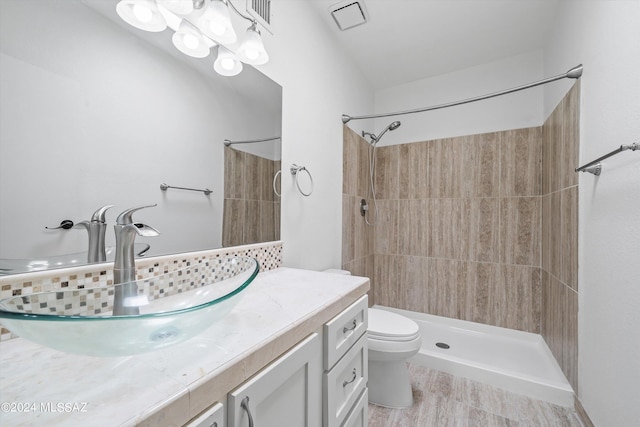 bathroom featuring vanity, a tile shower, and toilet