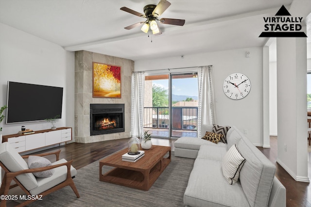 living room featuring beam ceiling, a tile fireplace, ceiling fan, and dark hardwood / wood-style flooring