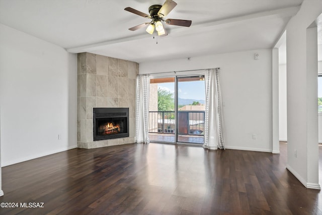 unfurnished living room featuring beamed ceiling, a tile fireplace, dark hardwood / wood-style floors, and ceiling fan