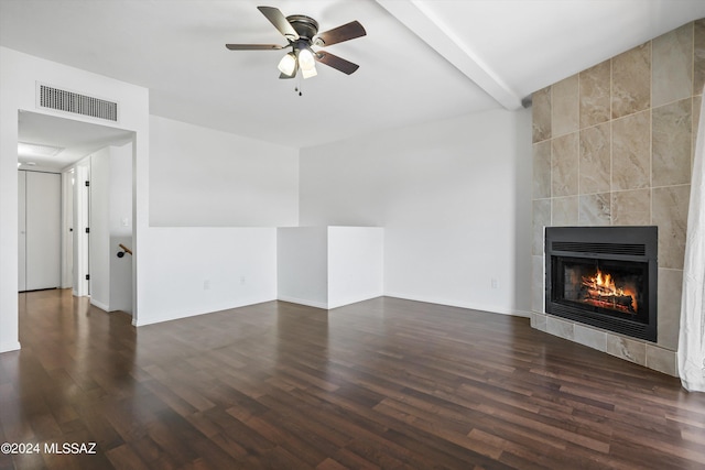 unfurnished living room with beamed ceiling, ceiling fan, dark wood-type flooring, and a fireplace