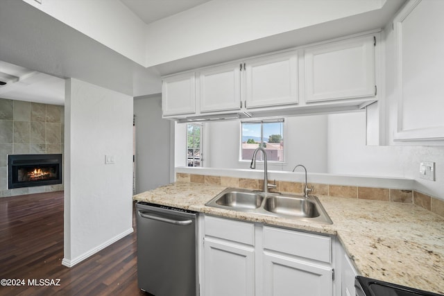 kitchen with white cabinetry, sink, a tiled fireplace, and dishwasher