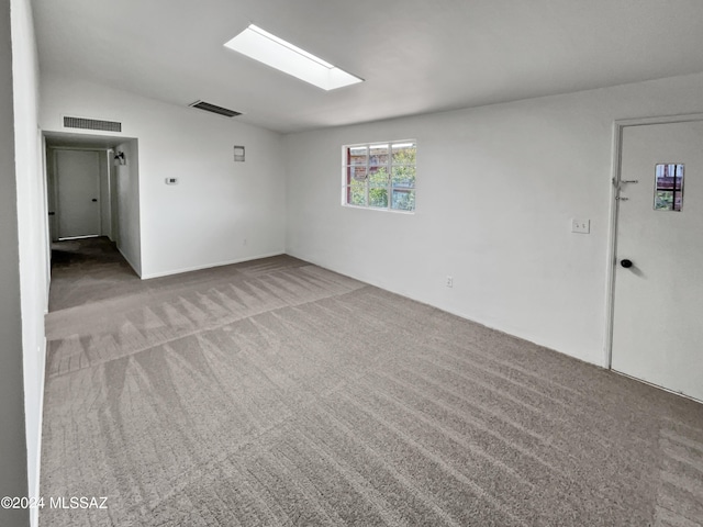 carpeted empty room featuring lofted ceiling with skylight