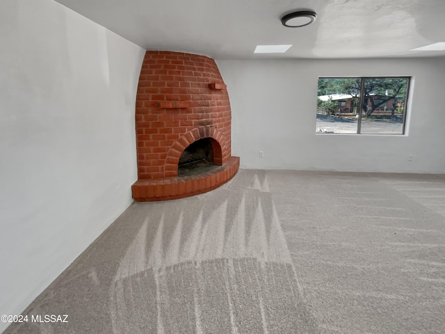 unfurnished living room featuring carpet flooring and a brick fireplace