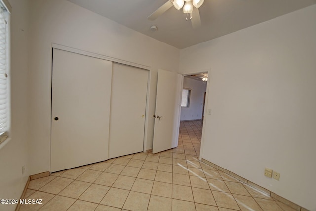 unfurnished bedroom featuring ceiling fan, light tile patterned floors, and a closet