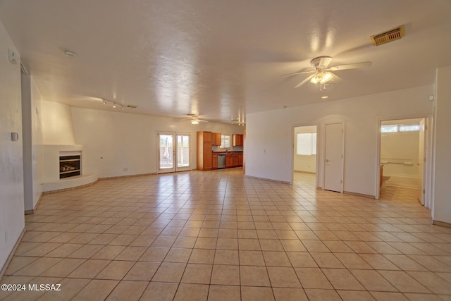 unfurnished living room with ceiling fan, a fireplace, and light tile patterned floors