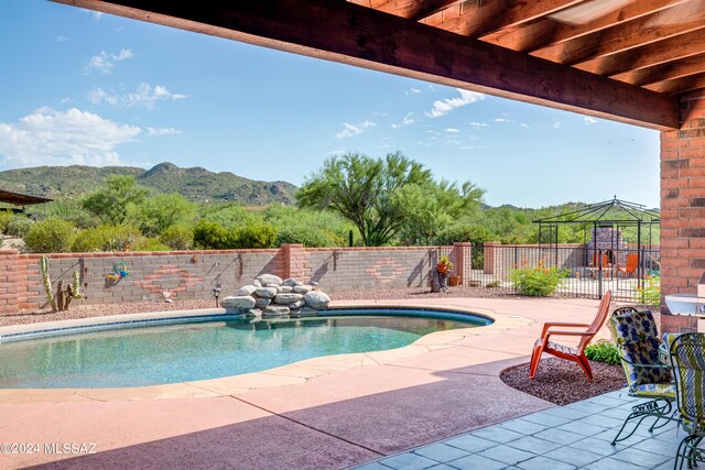 view of swimming pool featuring a fenced in pool, a mountain view, a fenced backyard, and a patio