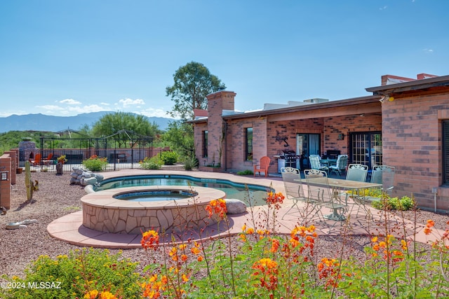 view of pool with a patio, a mountain view, an in ground hot tub, and fence