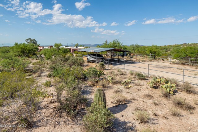 view of yard featuring a rural view, an exterior structure, an outdoor structure, a carport, and driveway