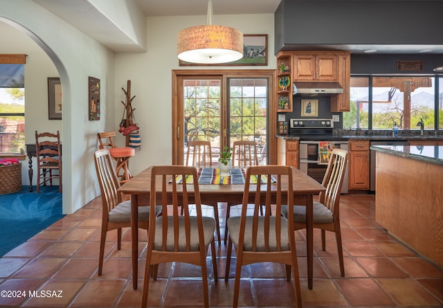 dining space featuring arched walkways, plenty of natural light, and dark tile patterned floors