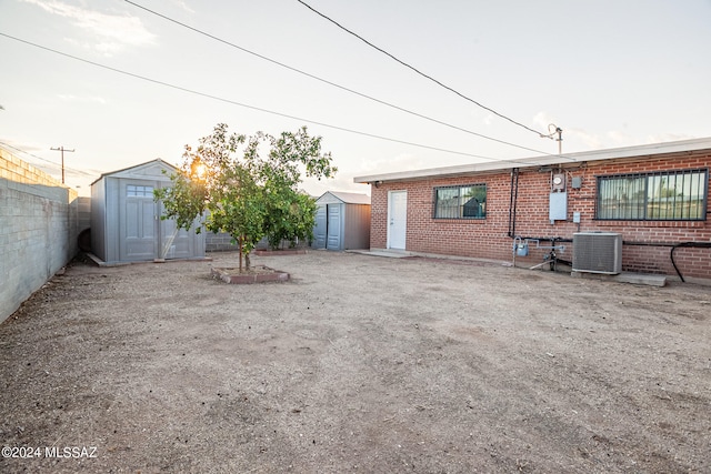 back of house with central AC unit and a shed