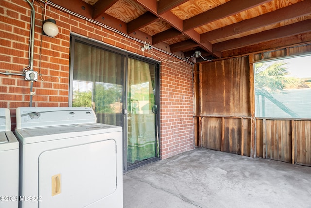 laundry room featuring plenty of natural light, brick wall, and washer and dryer