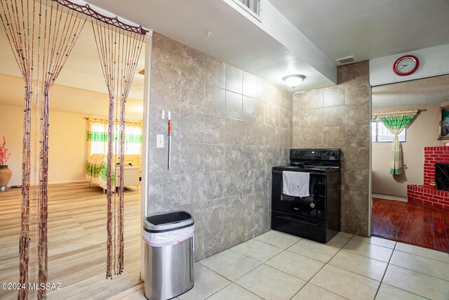 kitchen featuring tile patterned flooring, tile walls, and black range with electric stovetop