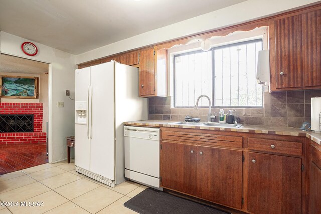 kitchen featuring backsplash, light hardwood / wood-style floors, a brick fireplace, and white appliances