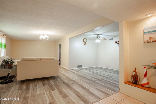 living room with light wood-type flooring and ceiling fan with notable chandelier