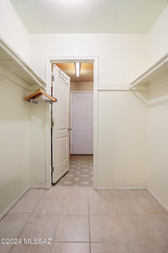 walk in closet with light tile patterned floors