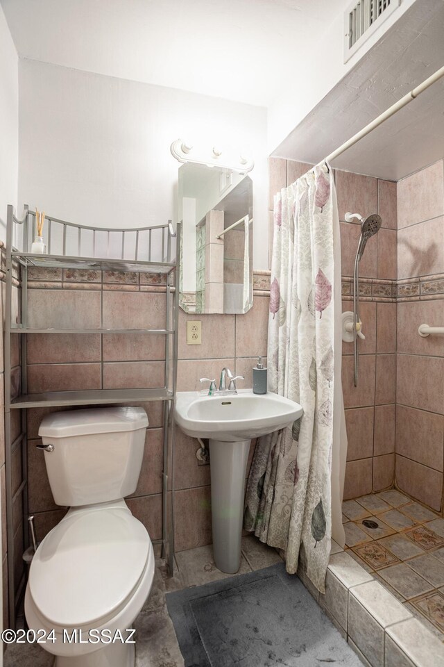 bathroom with toilet, a shower with shower curtain, tile walls, and tile patterned flooring