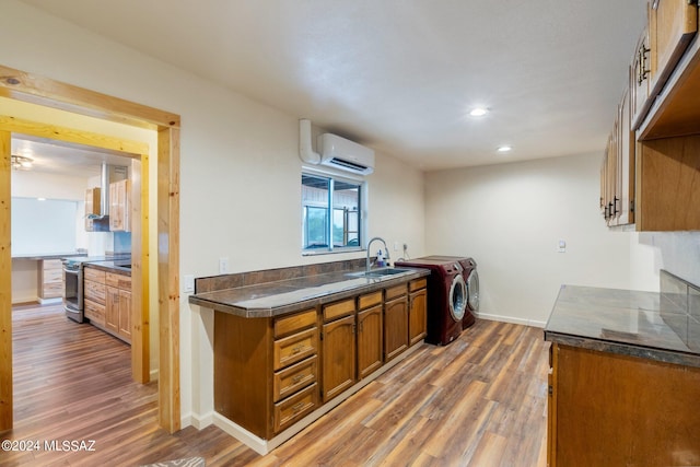 kitchen featuring a wall unit AC, washing machine and dryer, sink, dark hardwood / wood-style flooring, and electric range