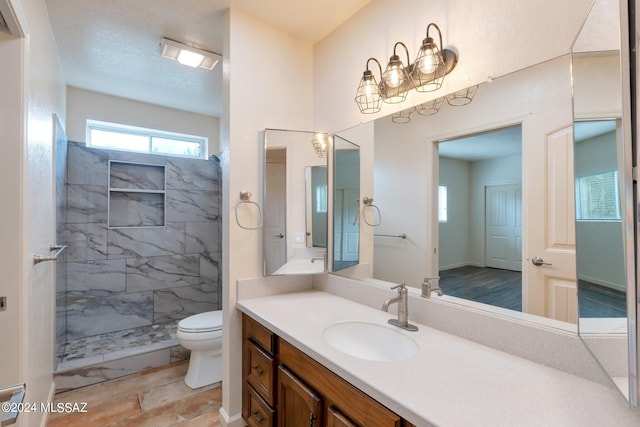 bathroom with vanity, tiled shower, toilet, and tile patterned floors