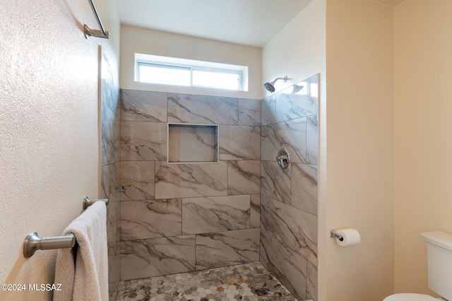 bathroom with tiled shower and toilet