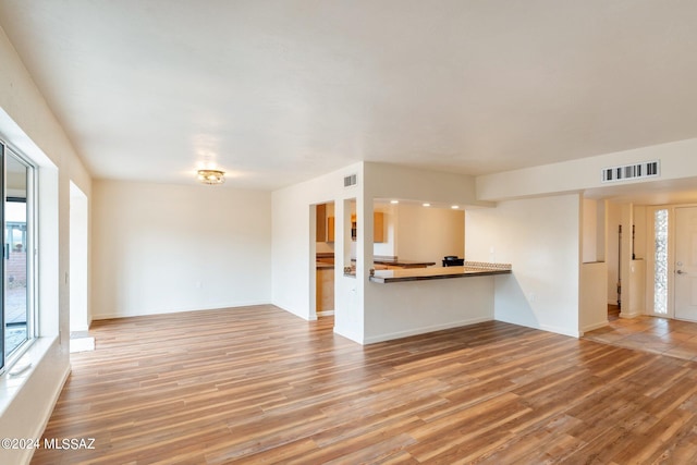 unfurnished living room featuring wood-type flooring and a wealth of natural light