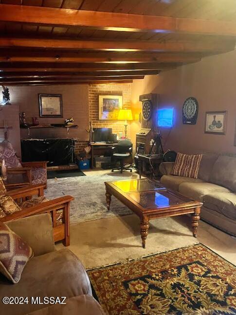 living room with beam ceiling, carpet, and brick wall