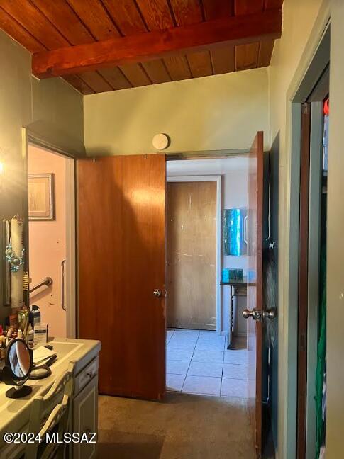 corridor featuring beam ceiling, wood ceiling, and light tile patterned floors